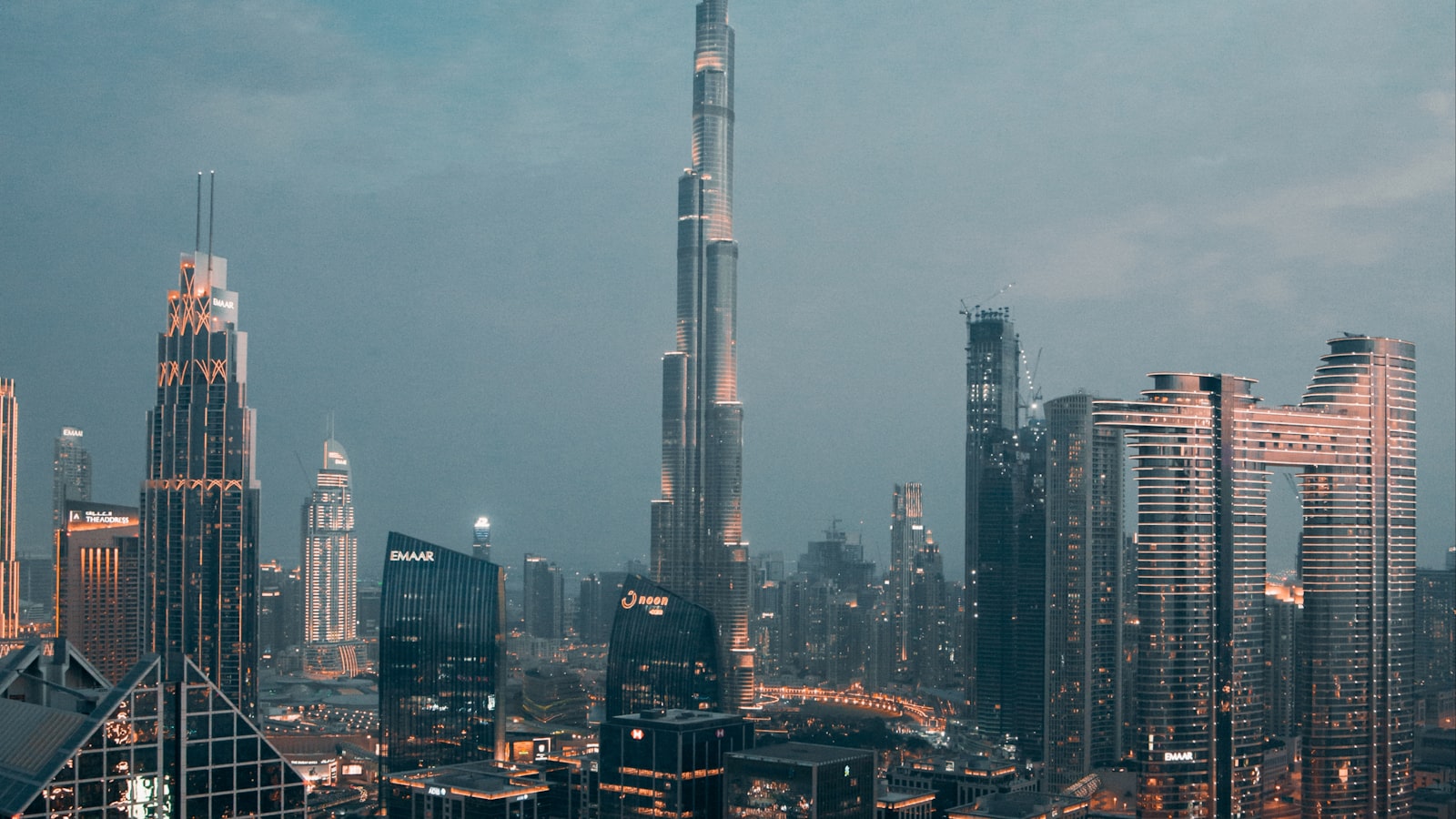 Aydınlatılmış şehir silueti ve otoyol kavşağının üzerinde yükselen Burj Khalifa